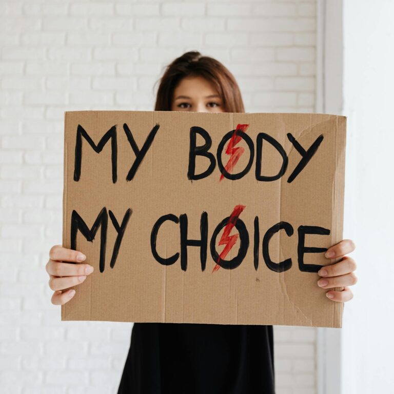 Woman holding 'My Body My Choice' sign, advocating for women's rights.