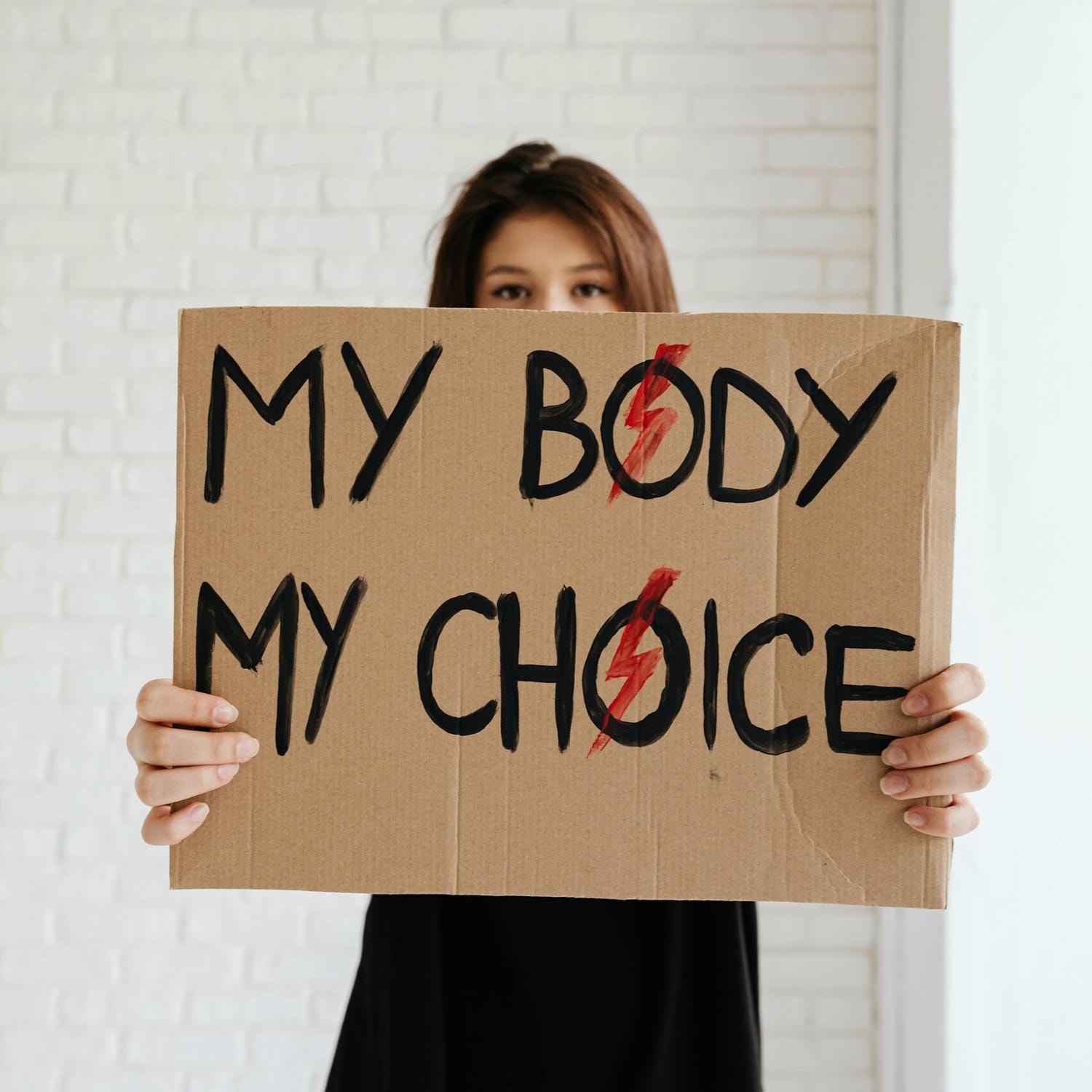 Woman holding 'My Body My Choice' sign, advocating for women's rights.